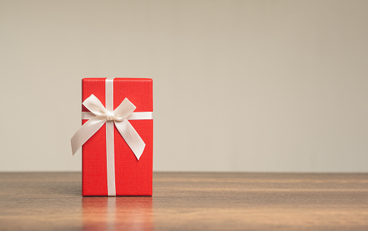 Gift of Joy. Red gift box on wooden table - Perfect for Christmas, celebrations, holidays, and special occasions