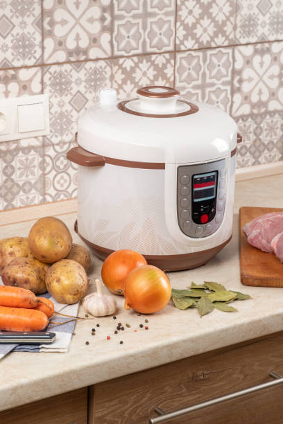istock Modern, light multi cooker and raw products on table in kitchen. Cooking stewed potatoes with meat in multicooker. 1898951437