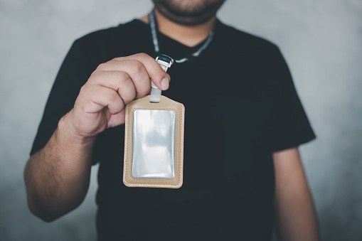 Hand holding blank id card badges with strap. Man wearing and show a ID card around neck mockup