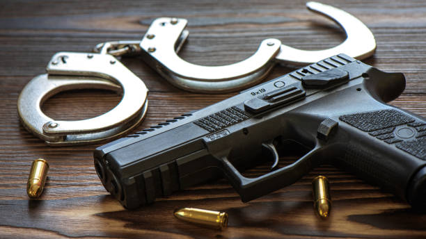 istock Semi automatic pistol with amunitions and handcuffs on wooden table. 1899042226