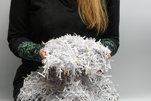A woman holds in her hands pieces of company documents destroyed in a shredder