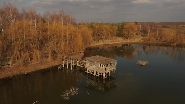 4k aerial top view Small fisherman house near lake. house is on stilts river pond Ukraine
