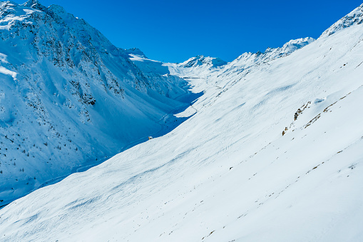 Skiers skiing in valley on 15 km long ski route from Schwarze Schneide at Rettenbach Glacier, at ski resort Soelden, Tirol.