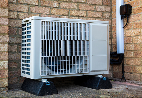 A single heat pump or compressor unit outside a modern house to provide air conditioning or warmth
