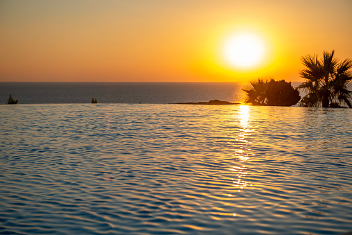 Infinity swimming pool and looking at a beautiful sunset and the sea view.