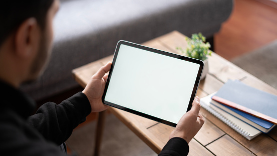 Mockup image of a woman holding digital tablet with blank white desktop screen in cafe