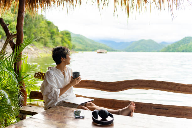 istock Asian Non-binary person remote working on lake house balcony. 1899242025