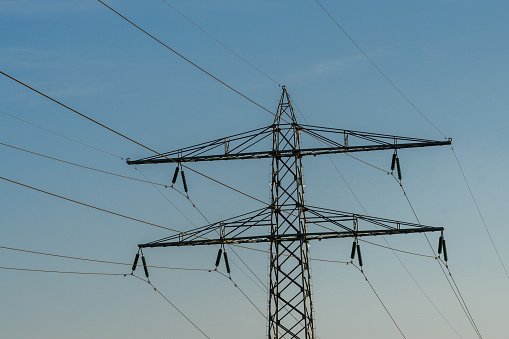Pylons with high voltage cables in the evening sun and blue sky with visible smog