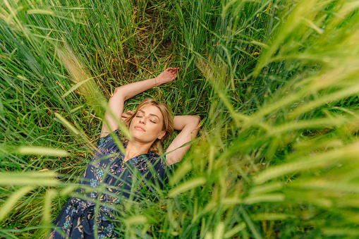 Photo of a young woman soaking in the warmth of the sun and embracing the tranquility of the rural landscape.