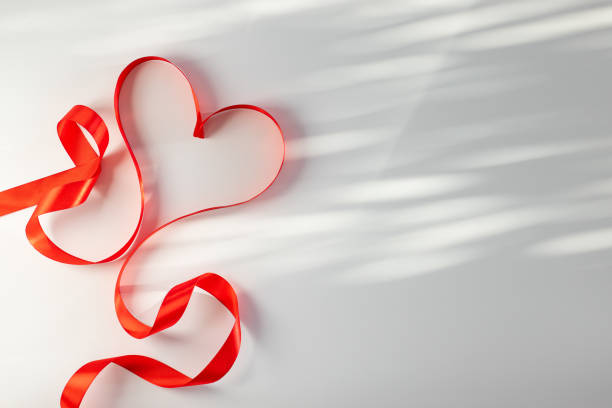 Valentine's Day background with red heart and ribbon on white background with copy space