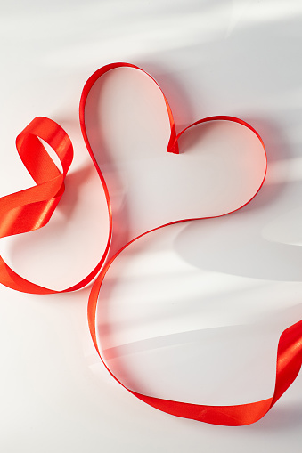 Valentine's Day background with red heart and ribbon on white background with copy space