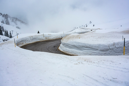 Curvy road in high snow near Pordoi pass, Sella Ronda, Dolomites, Italy.
