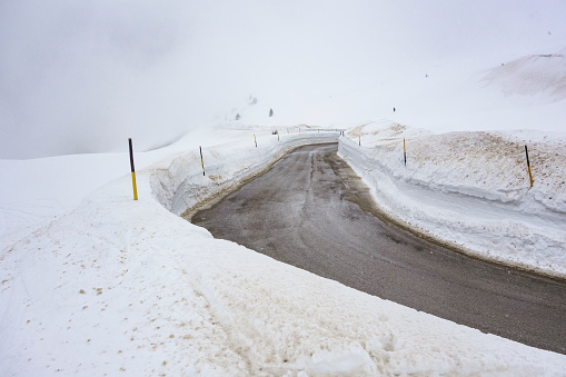 Curvy road in high snow near Pordoi pass, Sella Ronda, Dolomites, Italy.