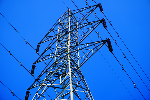 Steel electricity Pylon and High Voltage Power line Electricity transmission photo with blue sky background.