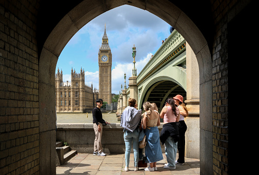International Tourists gather on the banks of the River Thames below Westminster Bridge to take a picture with the iconic Big Ben and the Houses of Parliament in London, England, UK