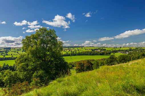 View of fields and a small village in the Lake District of Cumbria, England from the top of a hill.