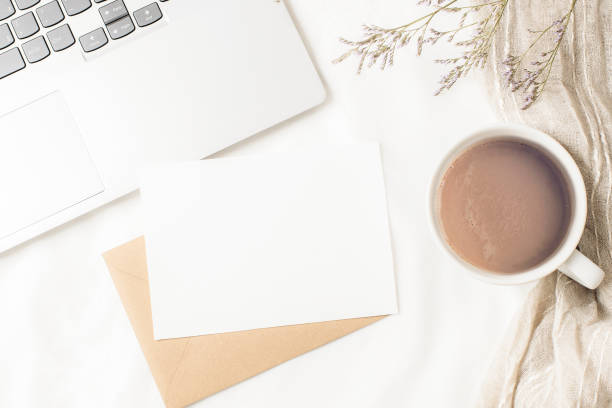 istock Coffee cup, laptop computer, envelope with blank card and dried flowers on white linen. Cozy workplace, comfort, hygge concept. Top view, flat lay, mockup 1899587143