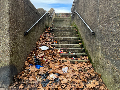 Old concrete steps covered in leaves and rubbish by a busy road in Walthamstow, London. January 2024