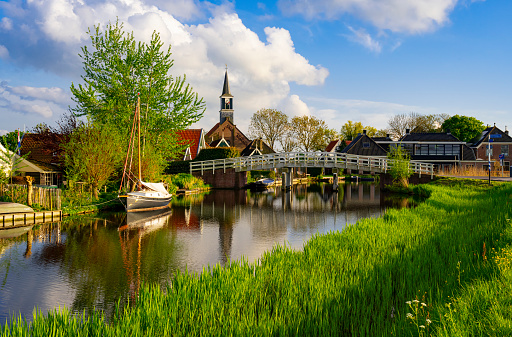 Small village of Driehuizen, Netherlands, with a church and a boat in a canal.