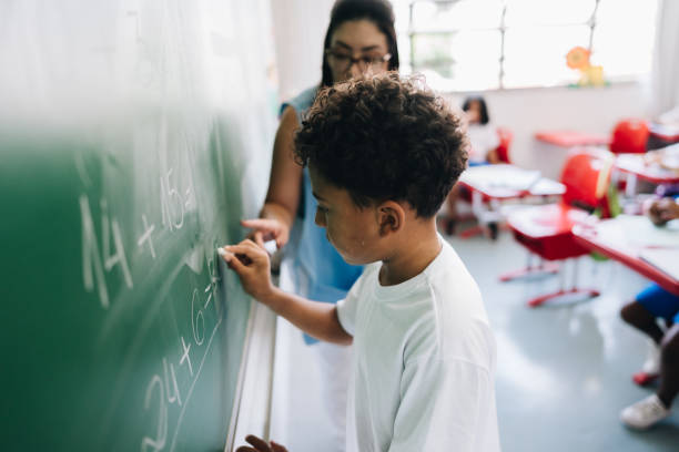 istock Student boy writing on chalkboard in classroom at school 1899648848