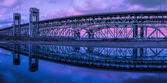 Gold Star Memorial Bridge in New London, Connecticut, the arching landmark suspending bridge over the Thames River, reflected symmetrical shapes over the water at twilight