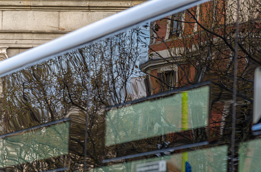 Urban detail, buildings reflected in the window of a bus