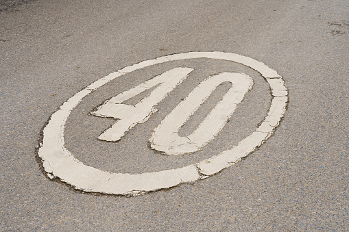 The speed limit sign is painted on the road with white paint. Close-up.