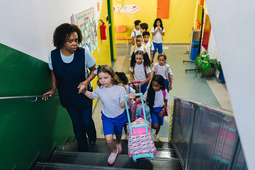 Teacher and her students going up stairs of the school