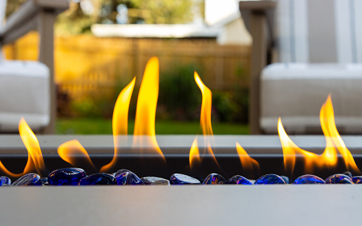 Close up of flames coming from an outdoor fire pit on a backyard patio.