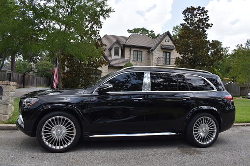 Houston, TX USA 07-27-2023 - A black metallic colored Maybach Mercedes-Benz GLS 600 SUV and a luxury home in Houston Texas