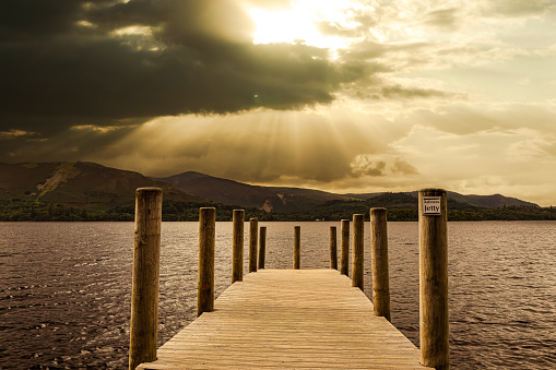 Digital composite sunset view of Derwent Water in the Lake District of Cumbria, England from a wooden jetty.