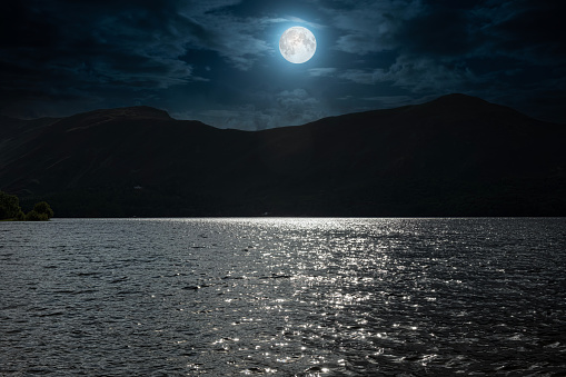 Digital composite view of silhouetted mountain seen in moonlight of Derwent Water in the Lake District of Cumbria, England.