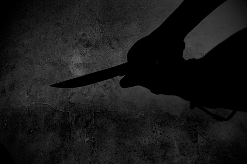 the shadow of a hand holding a knife in the darkness