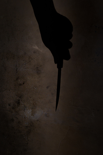 the shadow of a hand holding a knife in the darkness