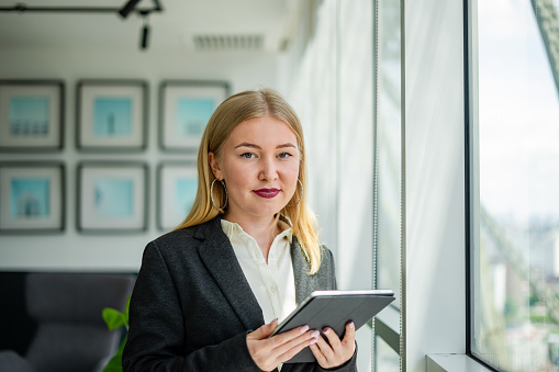portrait of central asian ethnic businesswoman holding digital tablet and looking at camera in office