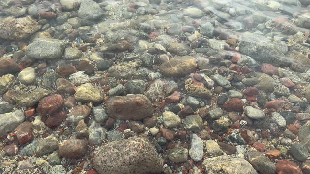 The base of the crystal-clear lake is adorned with petite pebbles.