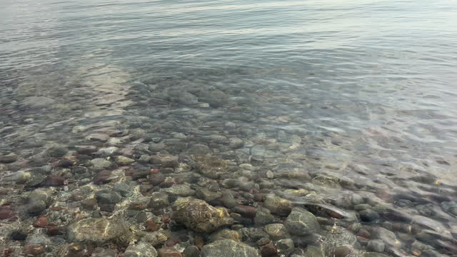 Clear lake waters reveal small pebbles nestled at the bottom.