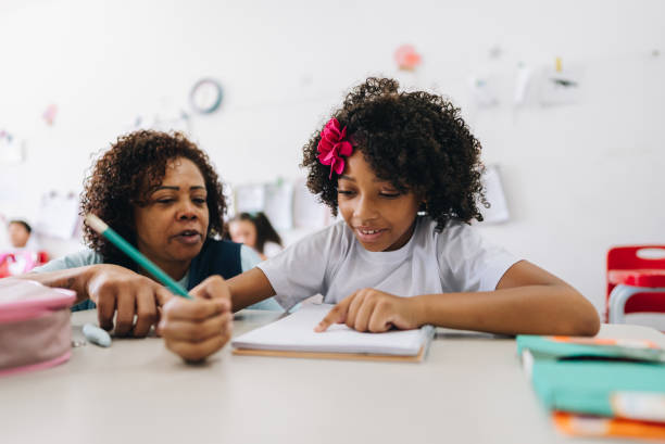 Teacher teaching her student on classroom at school