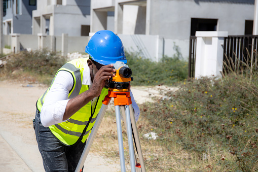 Surveyor man using theodolite at construction site, engineer survey measuring land and examining road, one person, industrial concept.