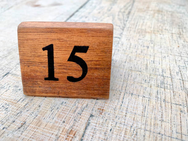 istock A wooden block with the number 15 placed on a white plastic table covering. 1899827065