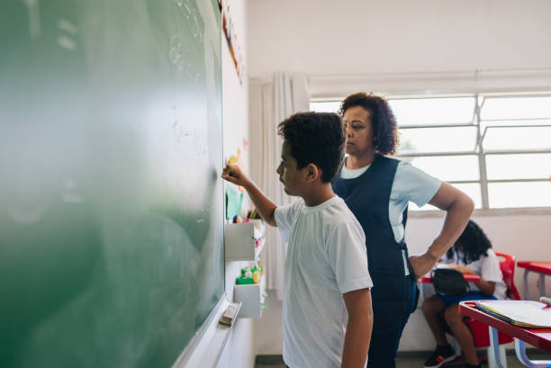 istock Student boy writing on chalkboard in classroom at school 1899829276
