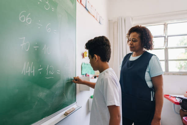 istock Student boy writing on chalkboard in classroom at school 1899829284