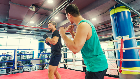 Color image of a box instructor and his student training on the ring. Copy space on left.