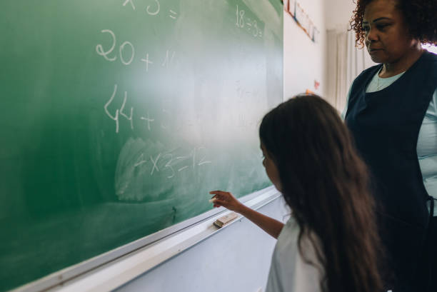 istock Student girl writing on chalkboard in classroom at school 1899836012