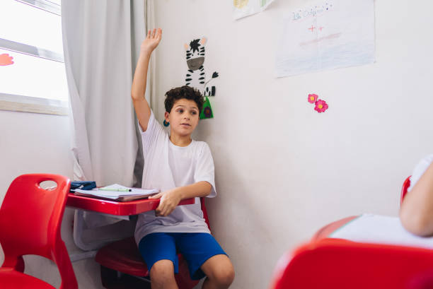 Boy student raising her hand to ask on classroom at school