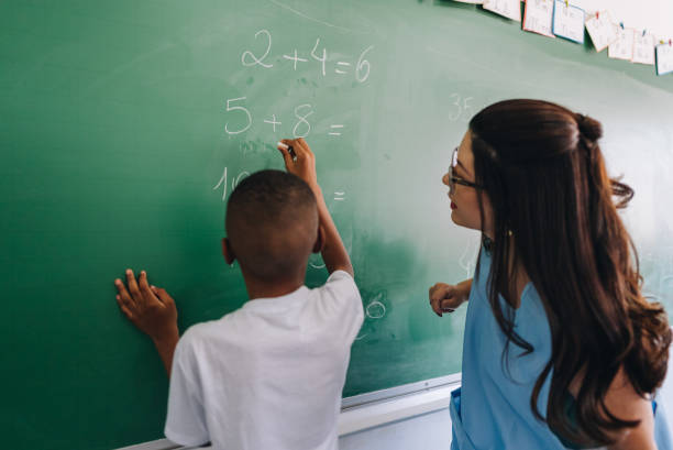 istock Student boy writing on chalkboard in classroom at school 1899837052