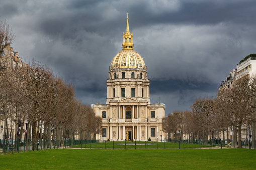 Sunlight hits the golden dome of Les Invalides, built under Louis XIV in 1677 to house invalids of his armies, with dramatic stormy sky, Paris, France