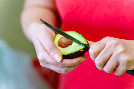 Girl's hands cutting avocado with pit