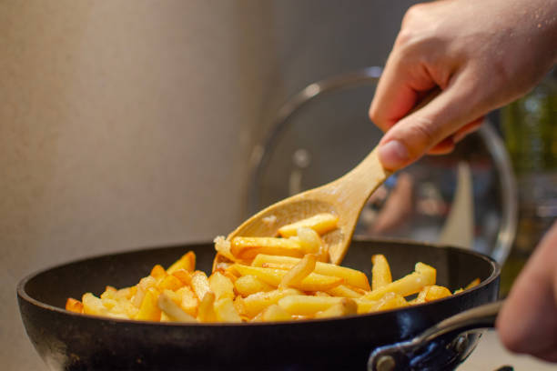 istock The process of preparing fried potatoes. Preparing a side dish for meat. A hand turns fried potatoes in a frying pan. 1899917841