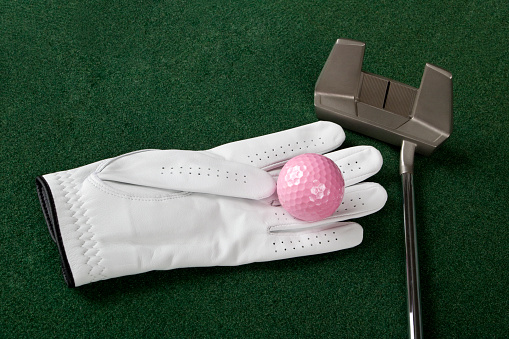 Indoor golf, putter on artificial turf with golf glove,  golf ball.